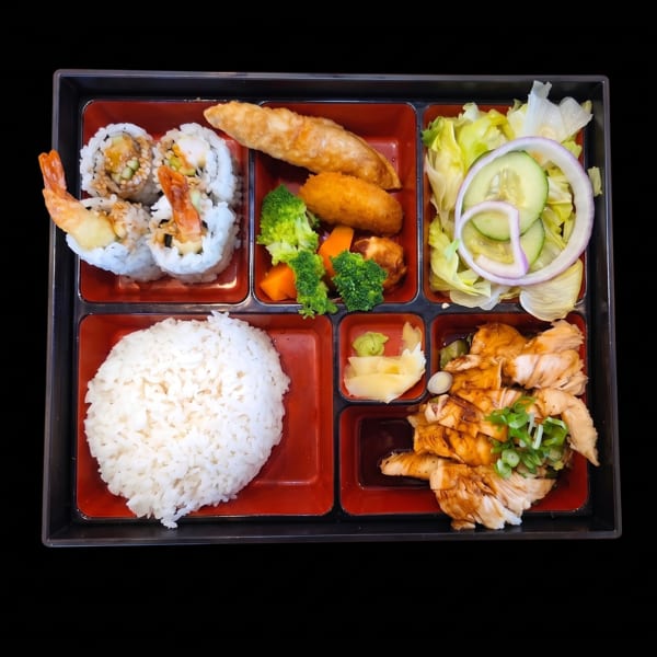 A bento box with sushi, rice, teriyaki chicken, salad, fried dumplings, and vegetables.
