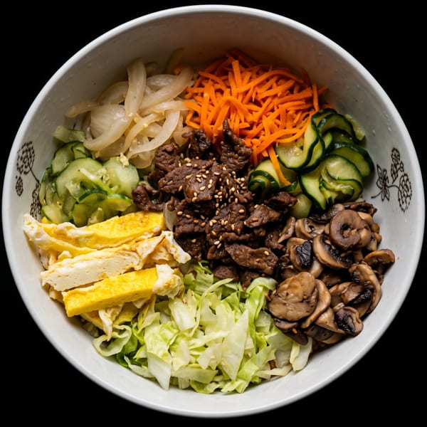 A colorful bibimbap bowl with beef, carrots, cucumbers, mushrooms, egg, and cabbage.