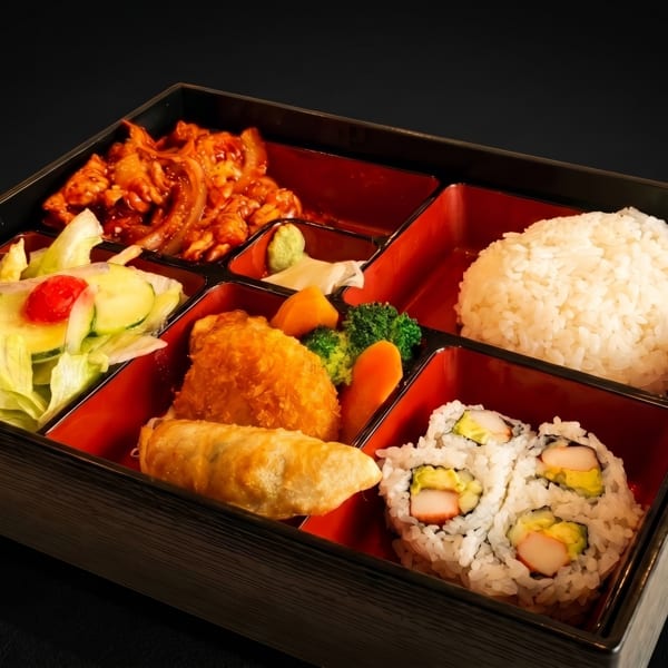 A bento box with sections of rice, sushi, salad, fried food, and spicy meat.